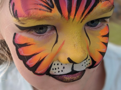 Face painting tiger Little girl orange and yellow striped tiger face
